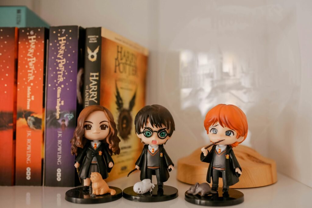 Miniature Harry Potter figurines displayed with book collection on a shelf.